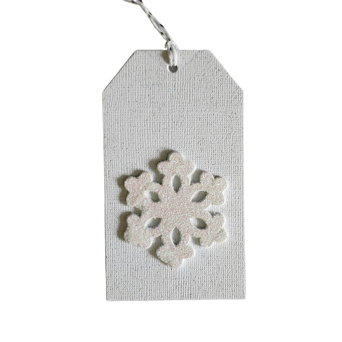 Handmade white Christmas gift tag with textured cardstock, dimensional sparkling snowflake, and white-and-silver cord.
Back product photo	Back of white Christmas snowflake gift tag with To and From stamped in black and white-and-silver hanging cord.